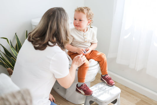Toddler boy potty training with mom on the big toilet