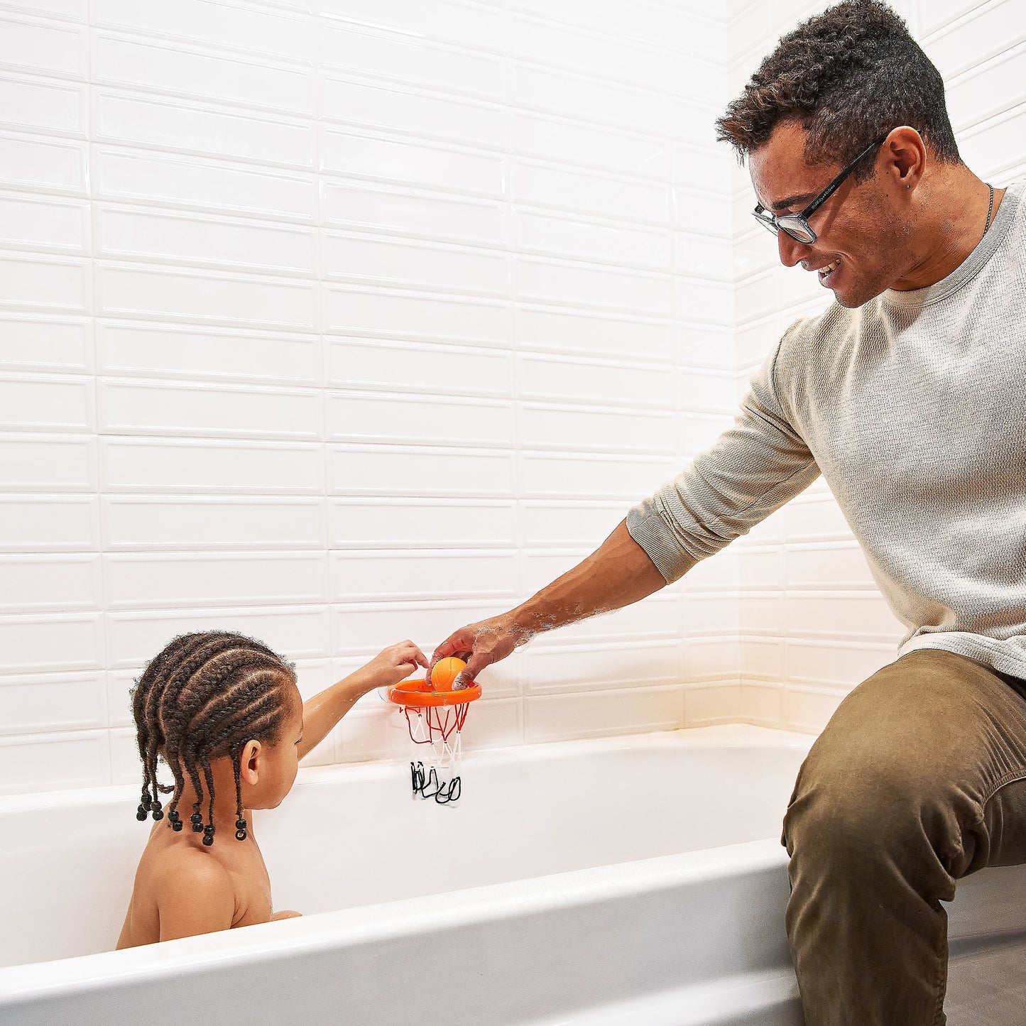 Man and child playing with a toy in a bathtub