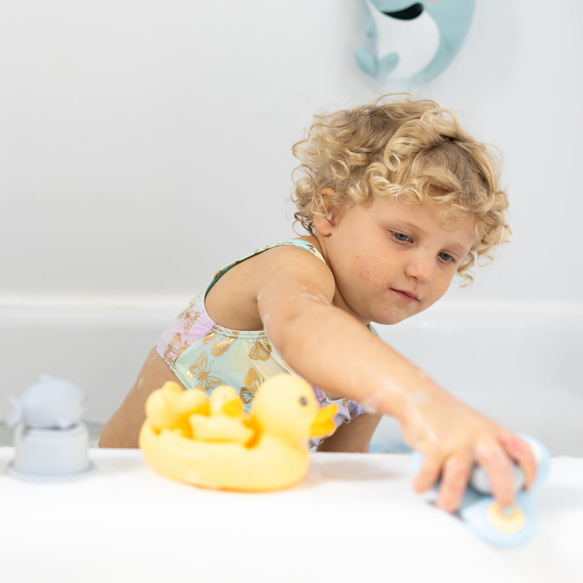 Child playing with bath toys on a bathtub ledge