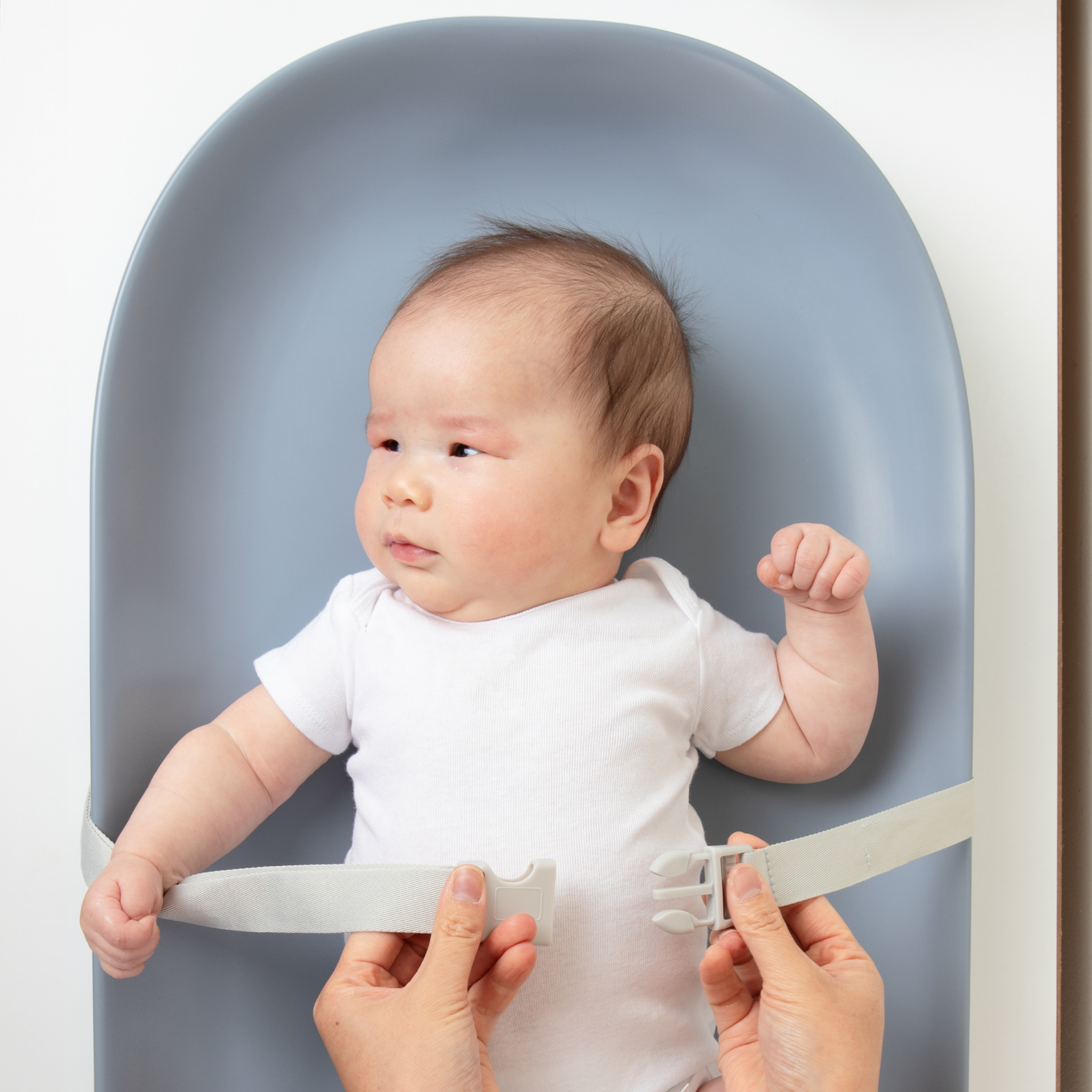 Mom strapping in baby to the premium changing pad while diaper changing