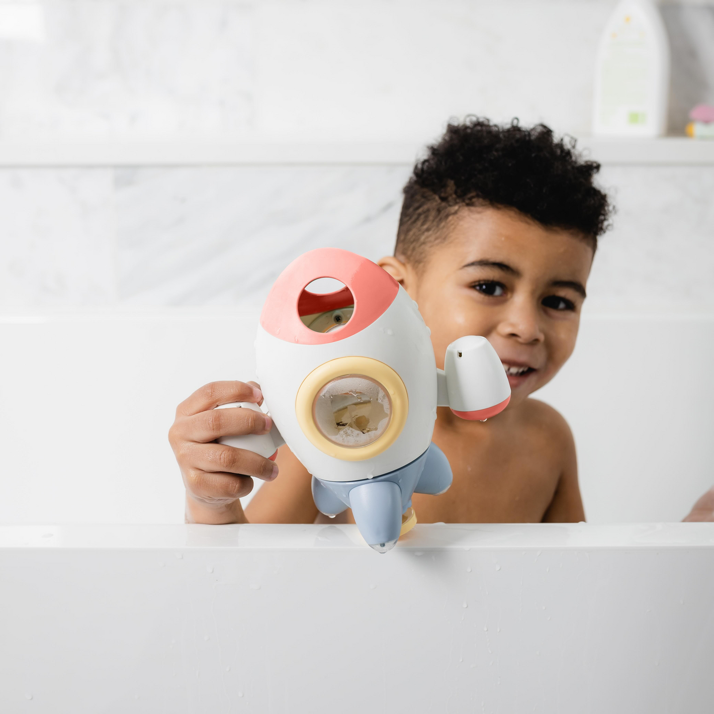 Toddler boy playing with rocket bathtime toy