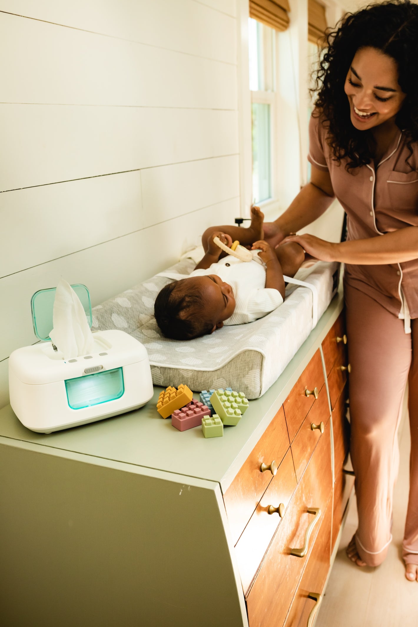 Mom changing baby diaper in nursery with changing pad and cloud cover and tiny bums wipe warmer