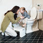 Woman teaching a child on a step stool next to a toilet in a bathroom.