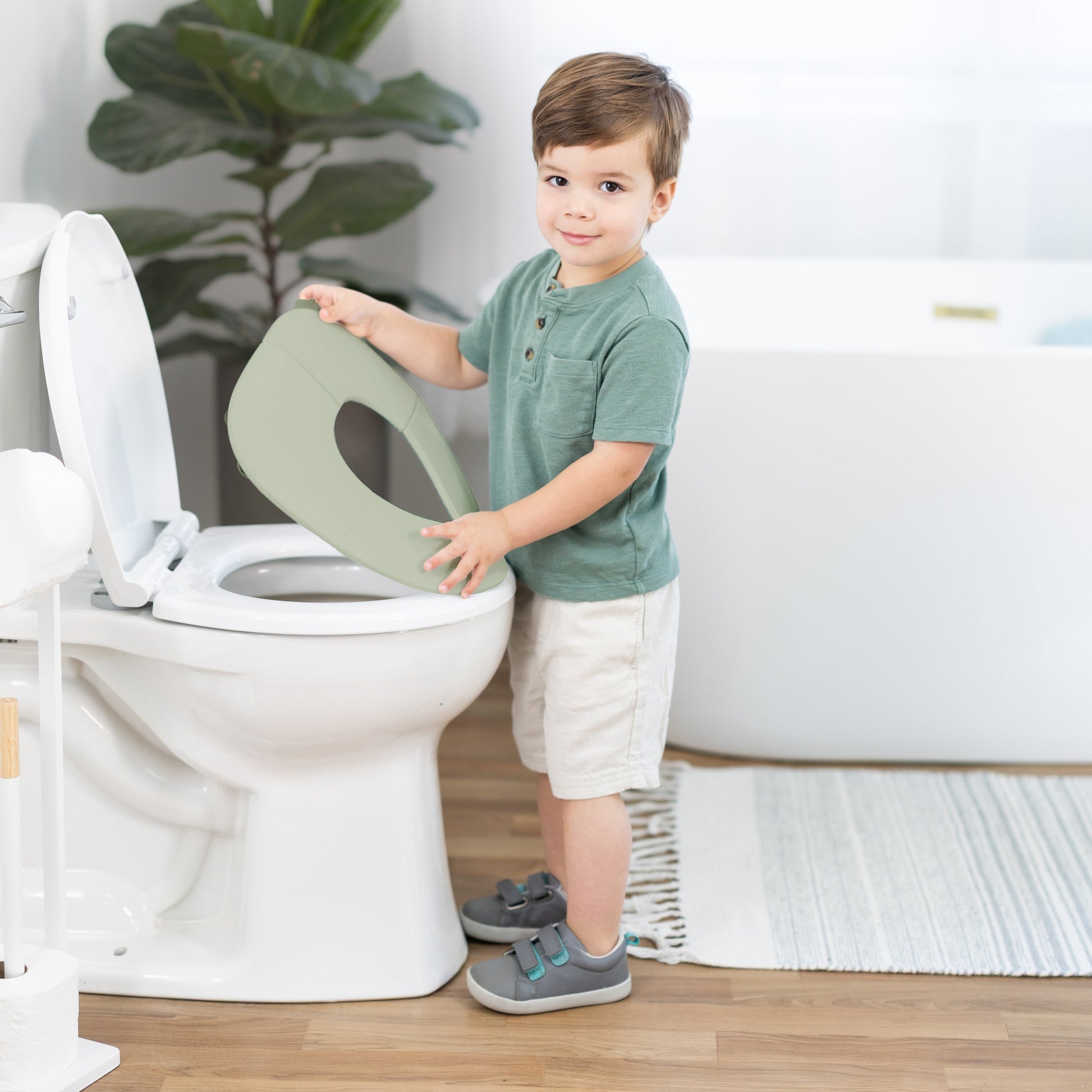 Child interacting with a toilet seat cover in a bathroom setting