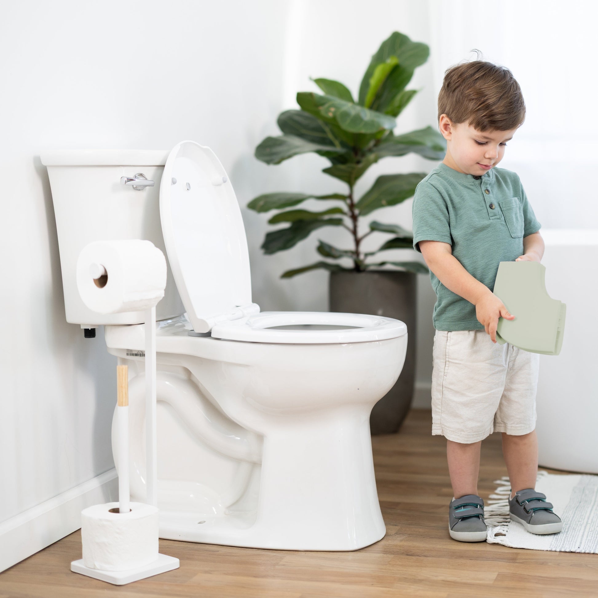 Child using folding travel potty seat in a bathroom setting