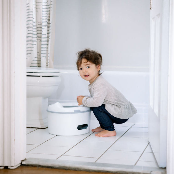 Toddler girl kneeling next to to potty chair