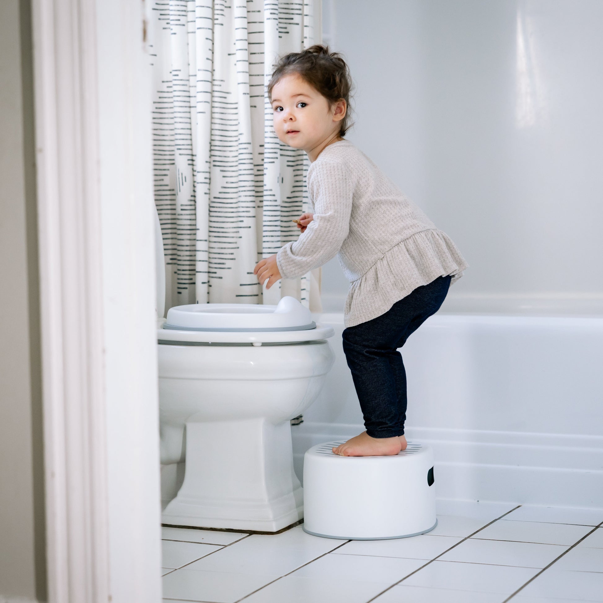 Toddler girl using step stool to potty train