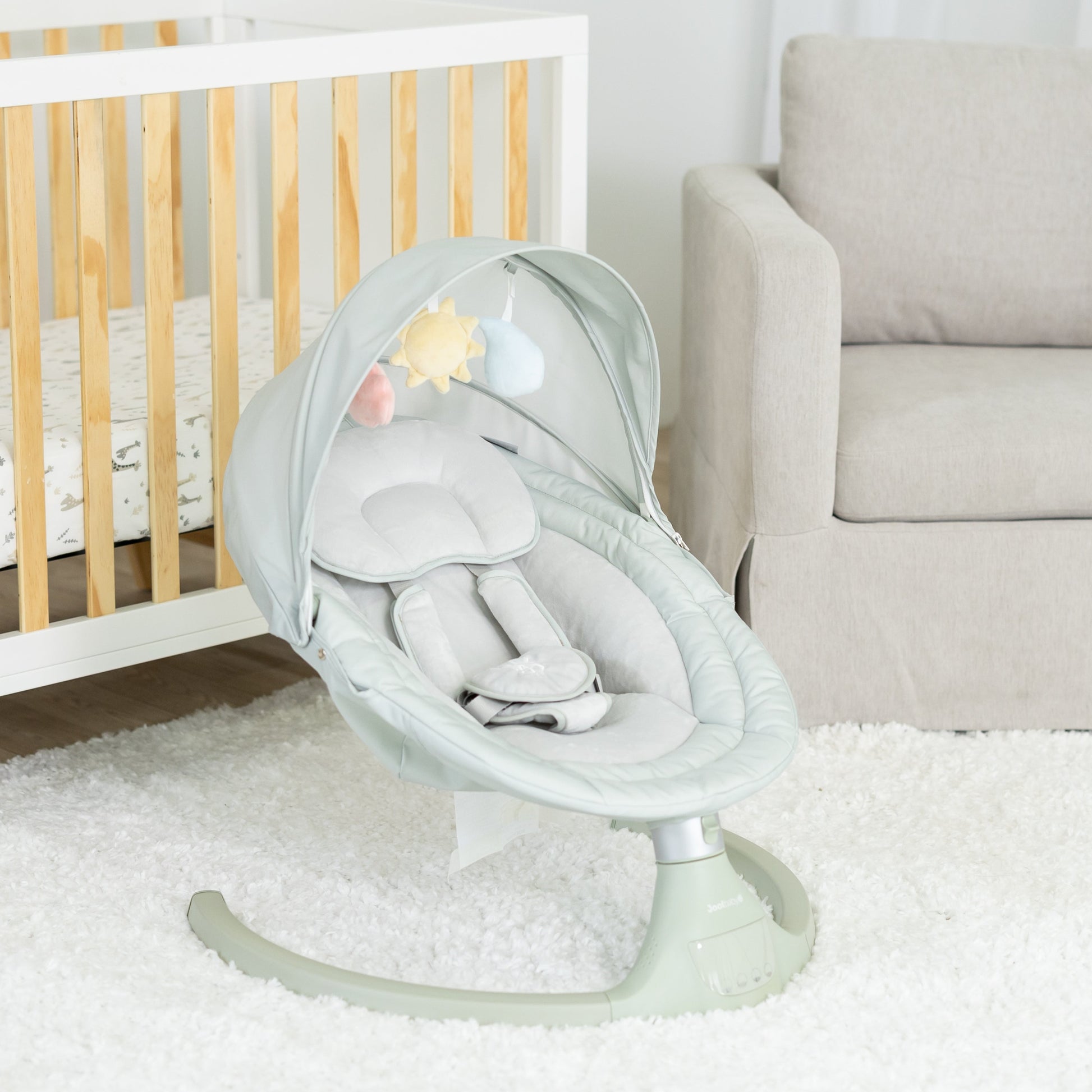 Baby swing in a nursery with crib and chair in the background