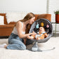 Woman sitting on the floor with a baby in a baby swing in a living room.
