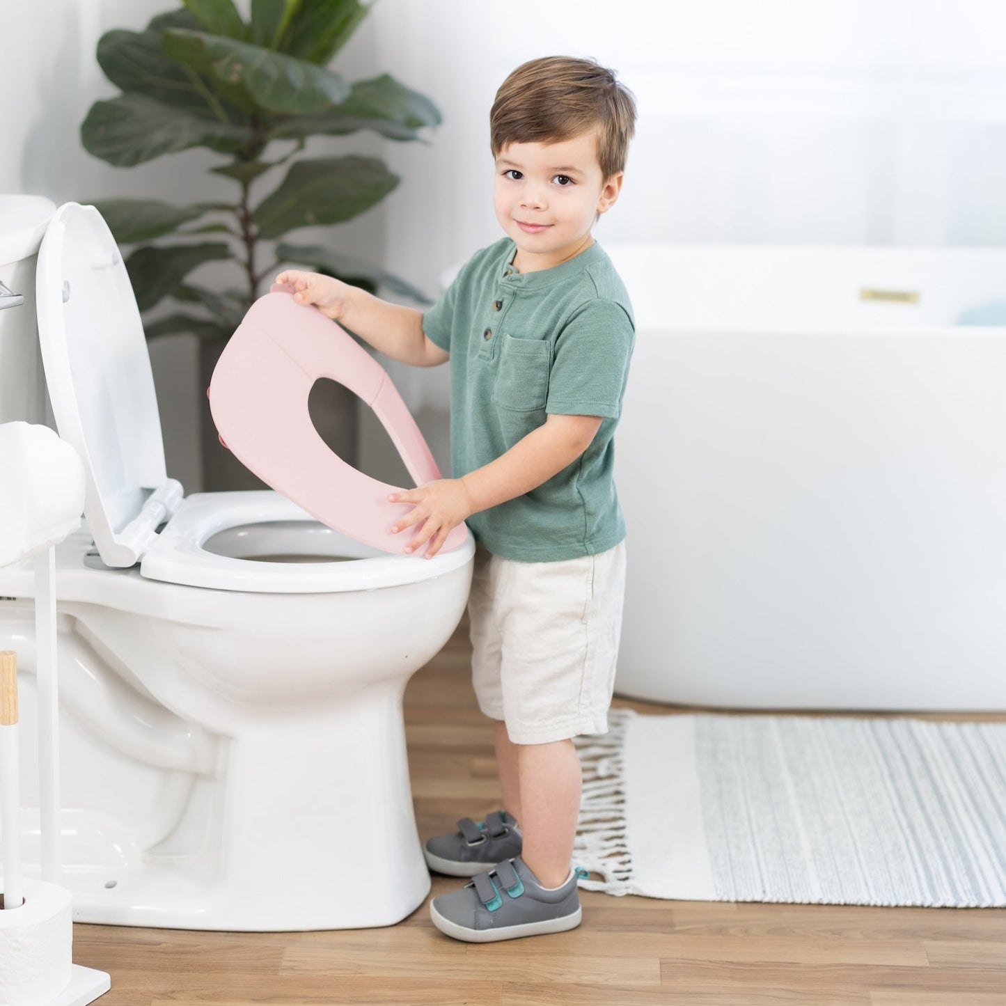Child interacting with a toilet seat cover in a bathroom setting