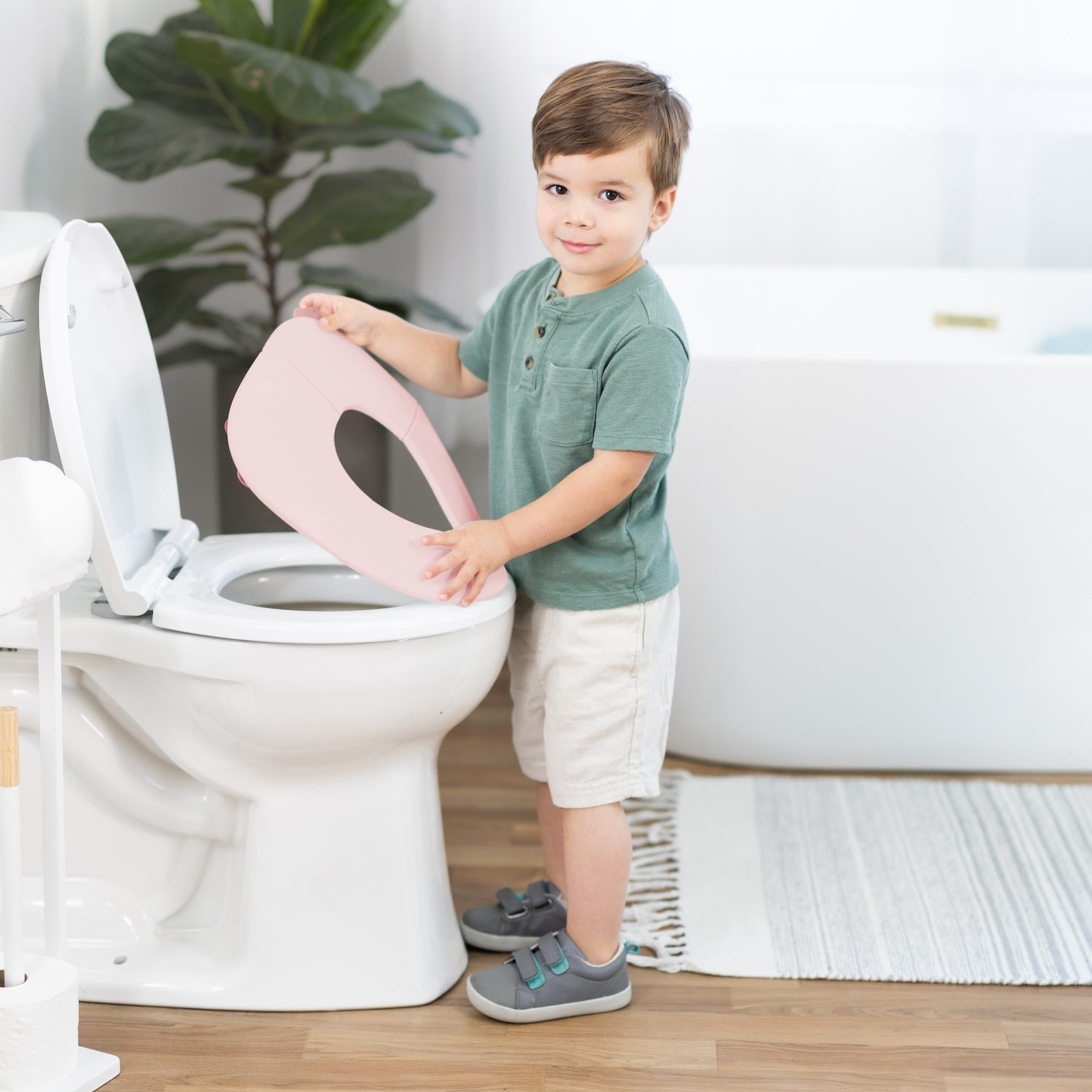 Child interacting with a toilet seat cover in a bathroom setting