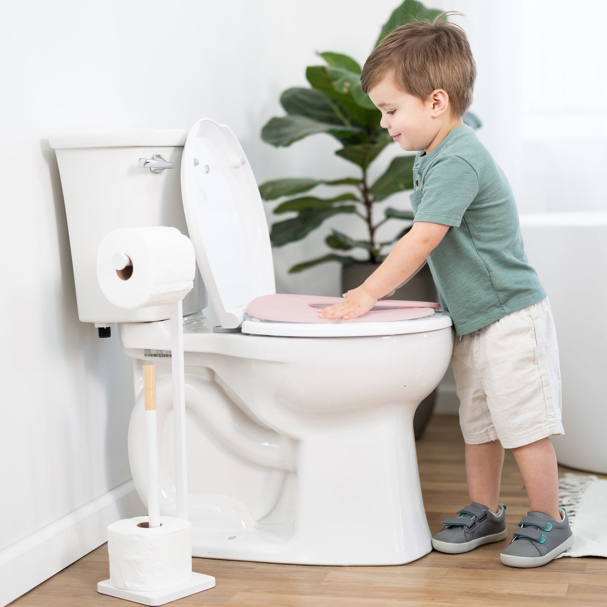 Child using a toilet with a seat up in a bathroom setting