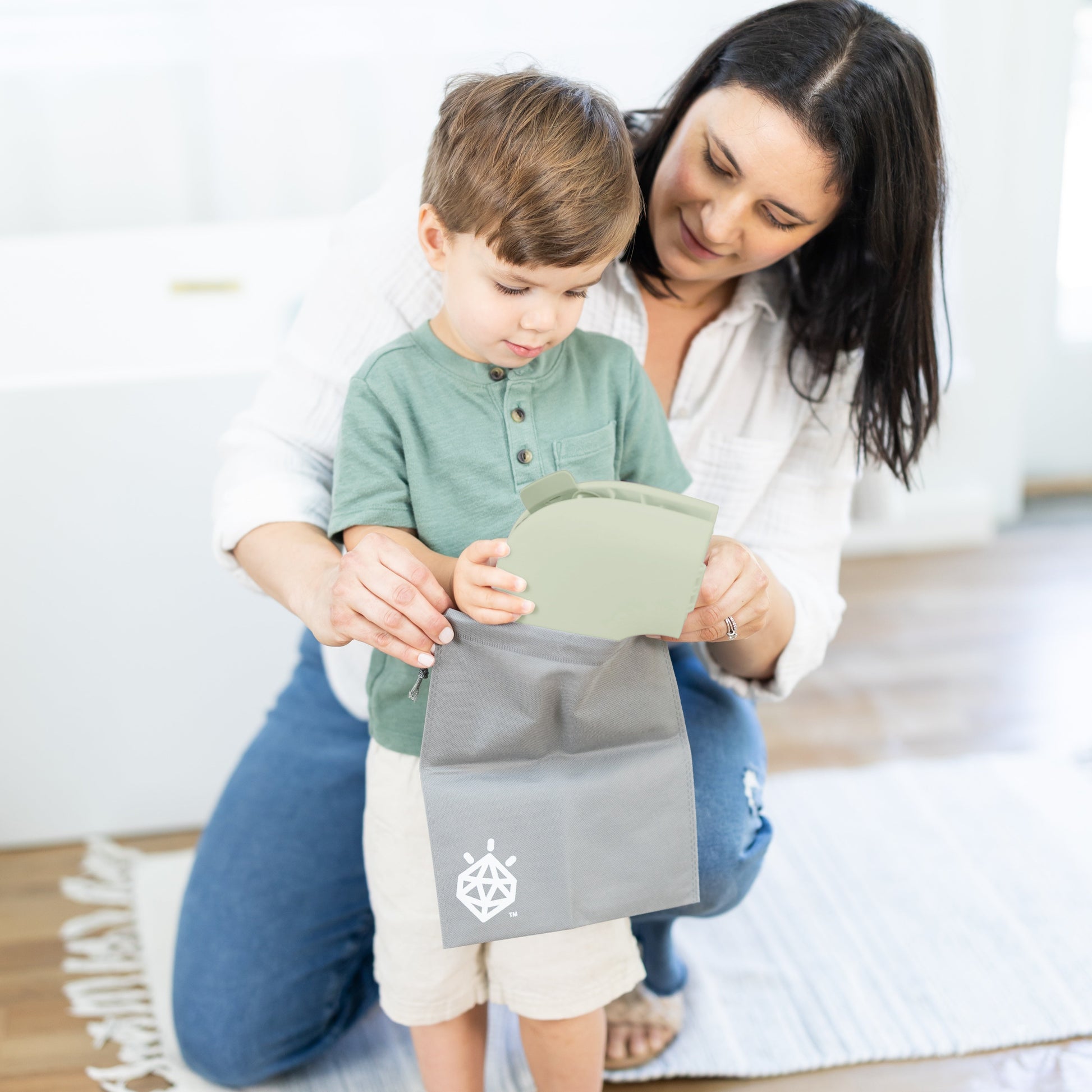 Mom and toddler folding the potty seat into the travel bag.