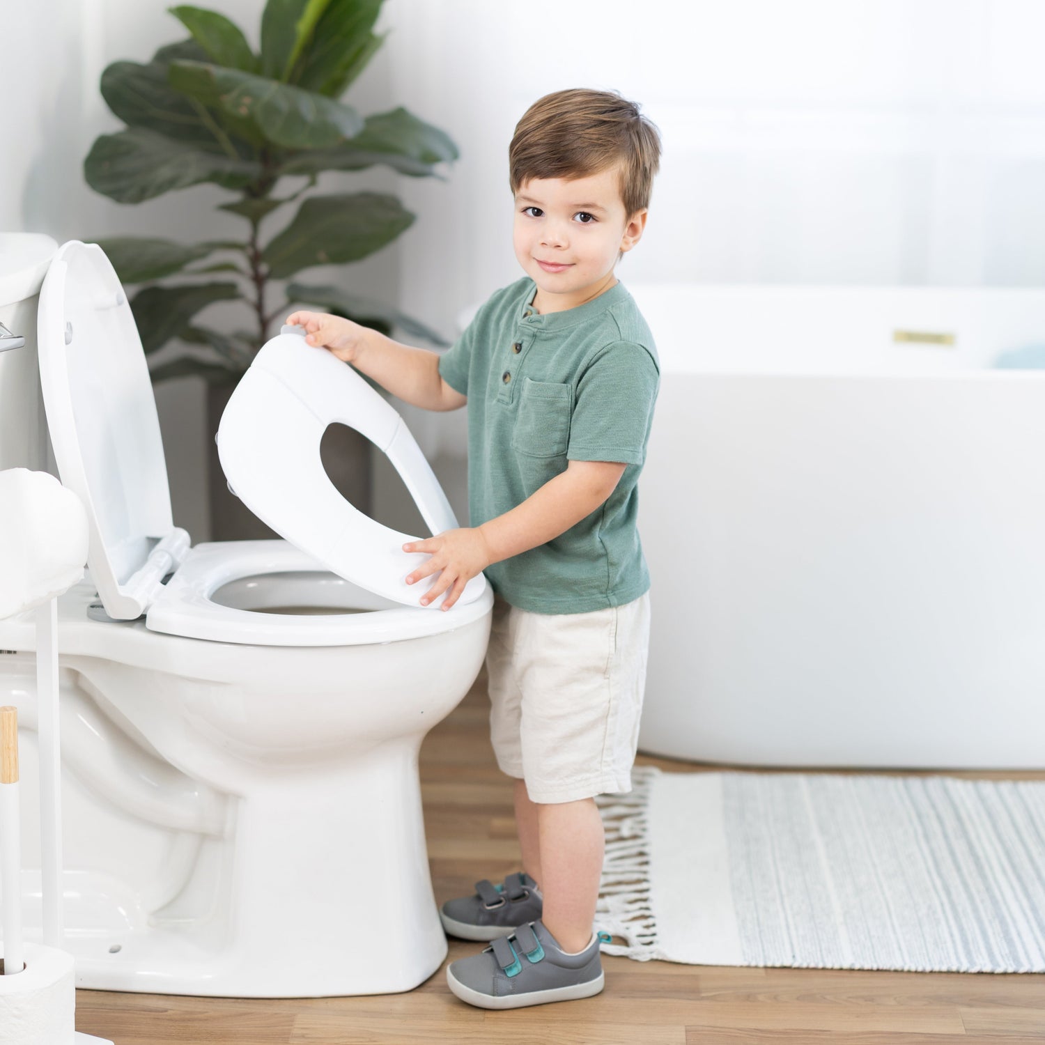 Child interacting with passport folding travel potty seat in a bathroom setting
