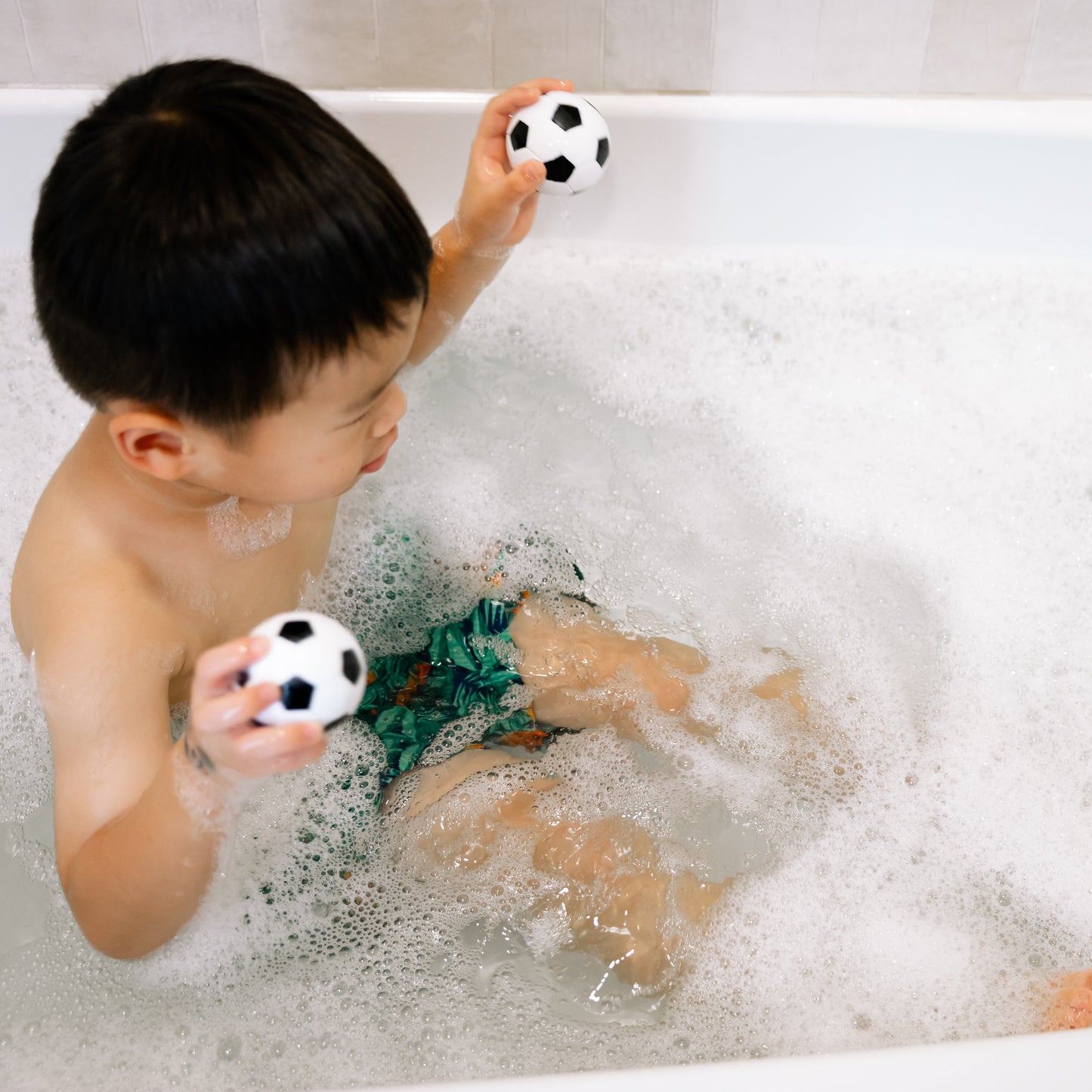Child playing with toys in a bathtub filled with bubbles